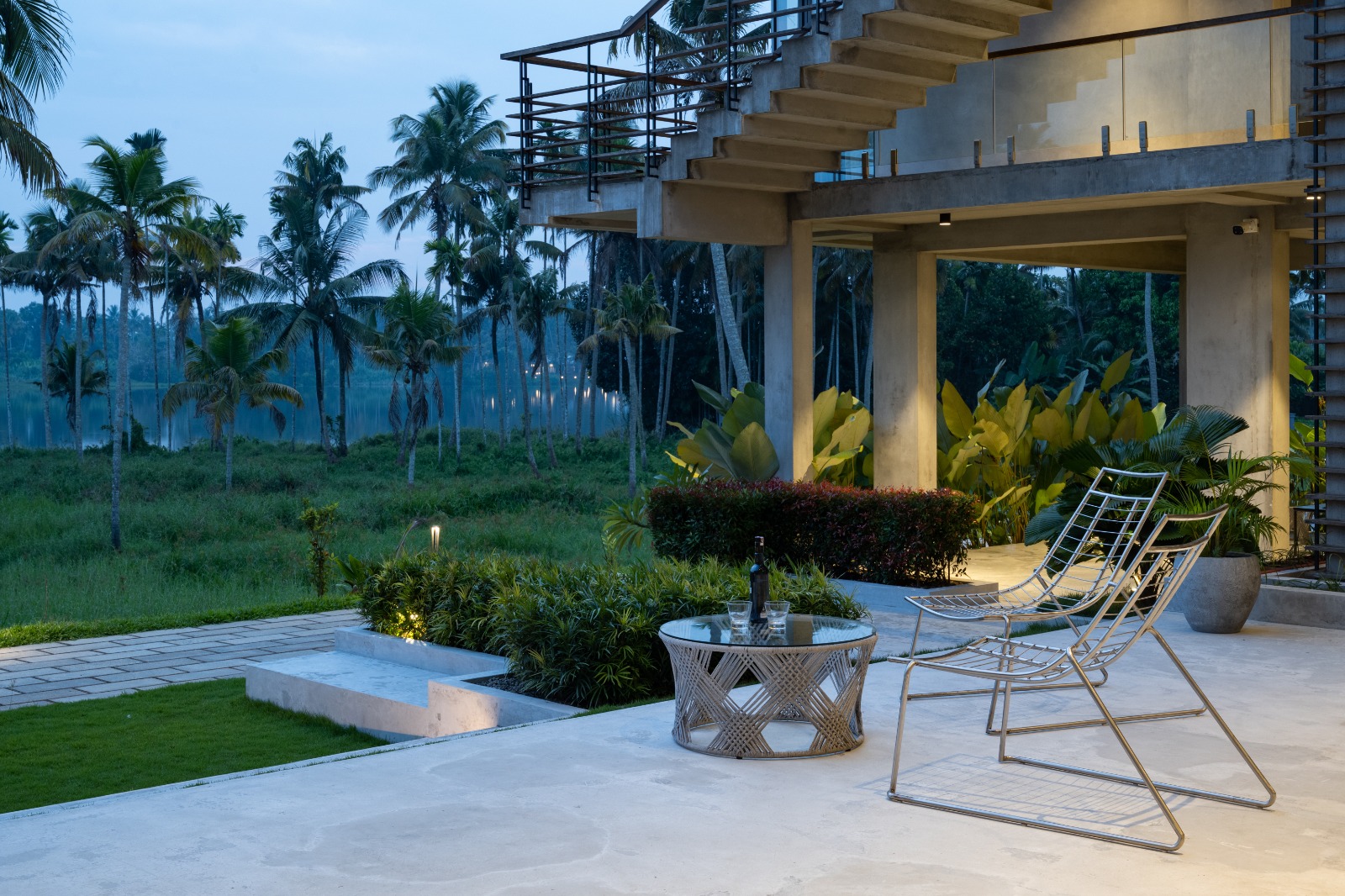 Sovnear ground terrace at evening with lounge chairs and palm-lined backwater views