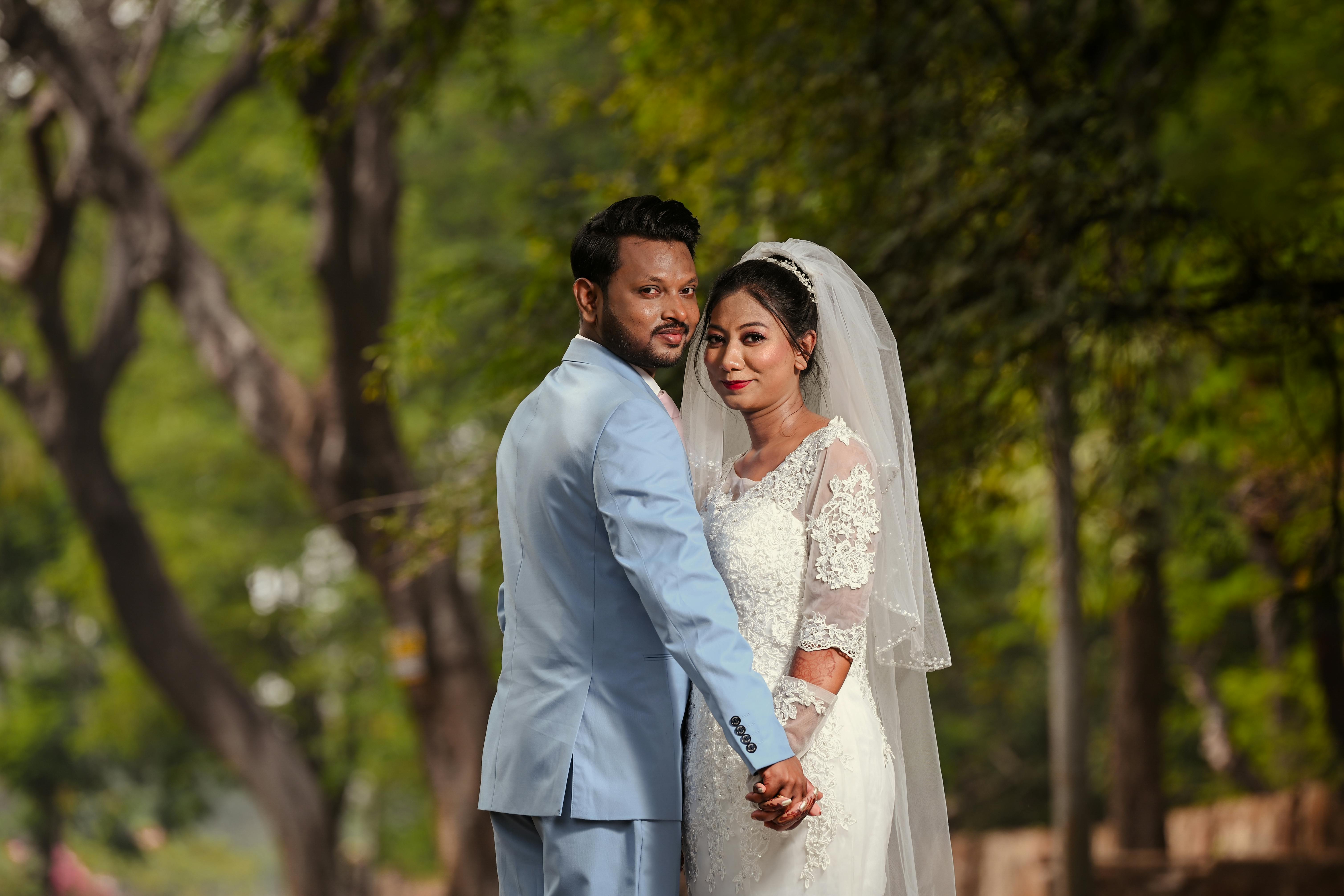 Christian wedding couple holding hands on a tree-lined avenue